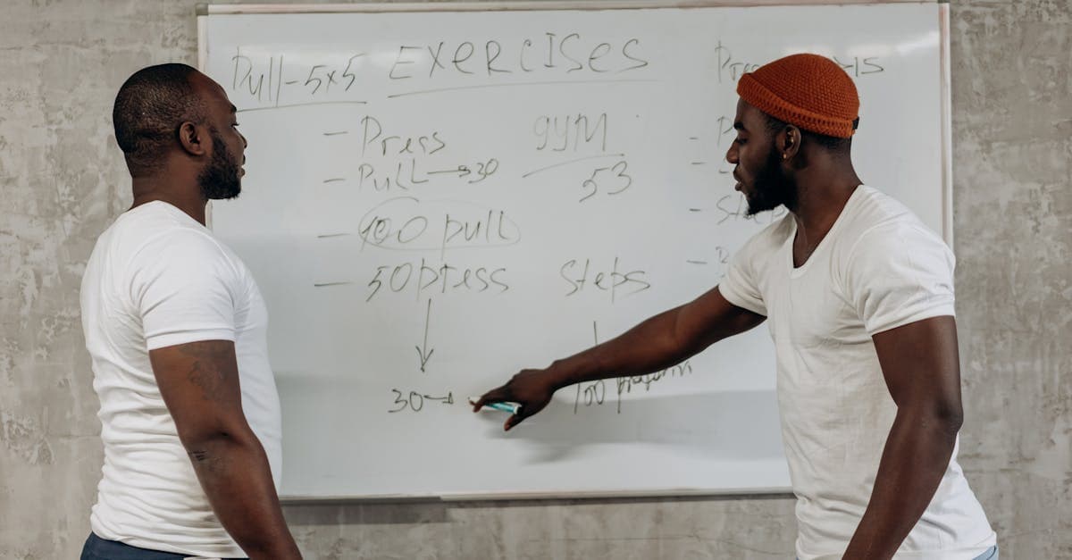 Coach sportif expliquant un programme d entraînement sur tableau blanc à un athlète en salle